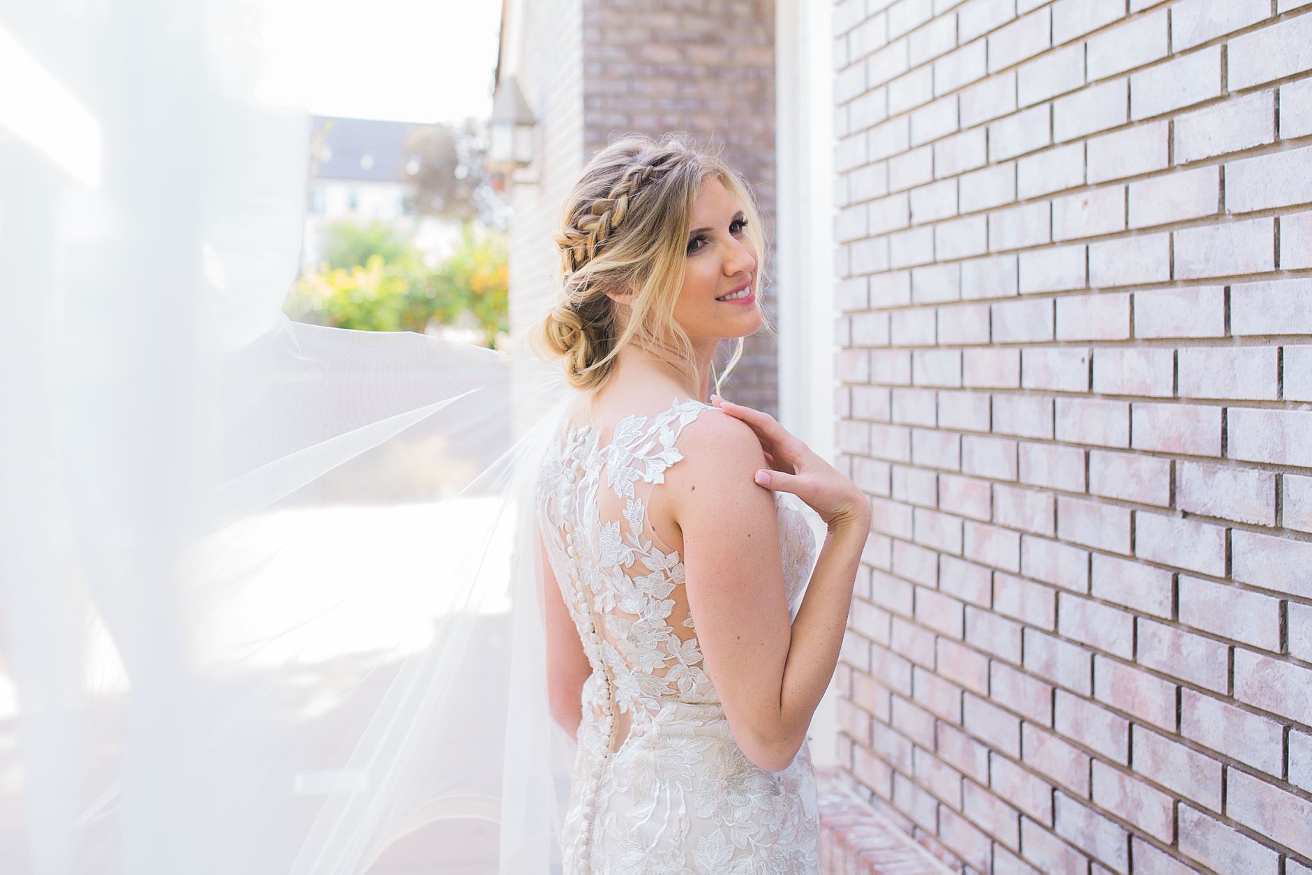 L'Auberge Del Mar Bride portrait posing by the brick wall. Gorgeous lacy dress and braided hair.