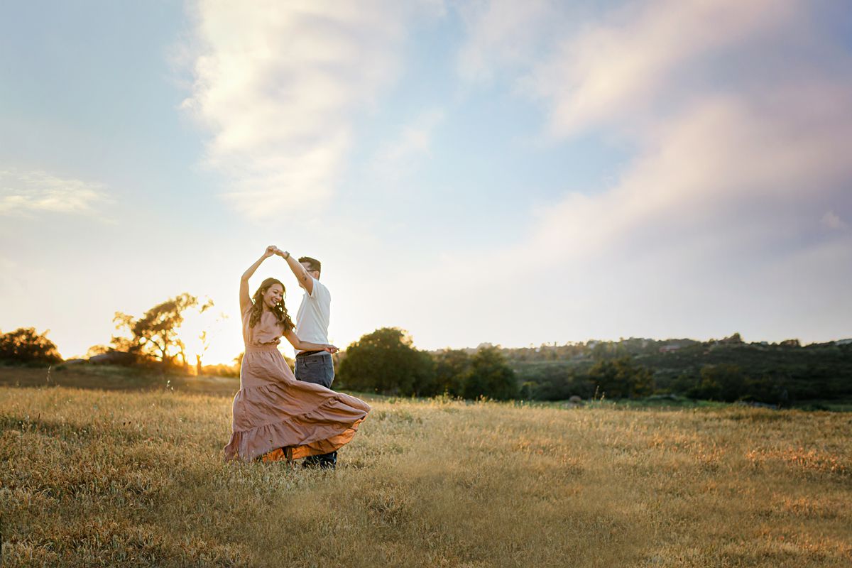 A couple dancing at a field, sunset time.