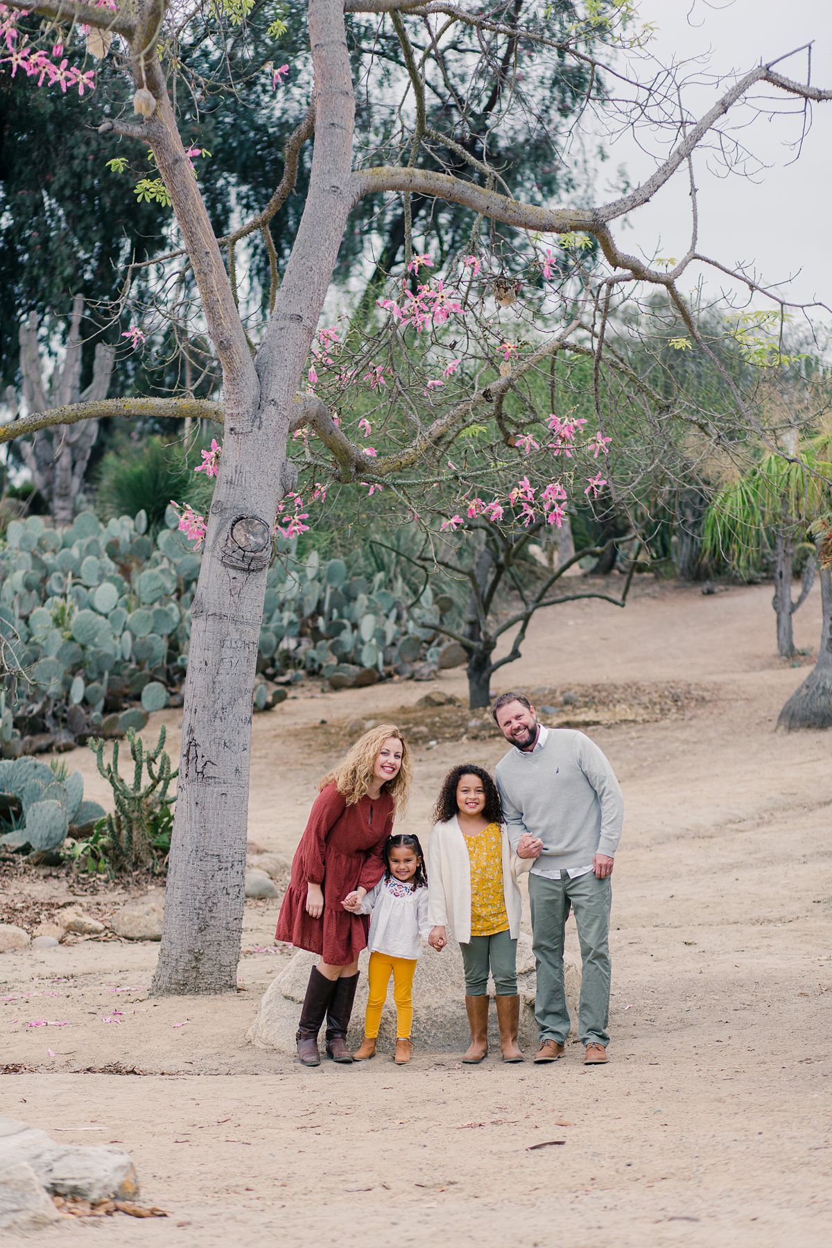 family standing in front of pink flower tree